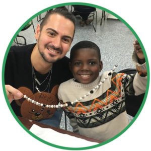 Young boy and volunteer create a beaded necklace